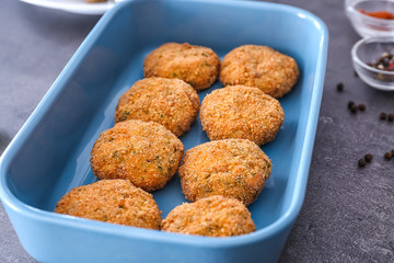 Baking dish with delicious salmon patties on table, closeup