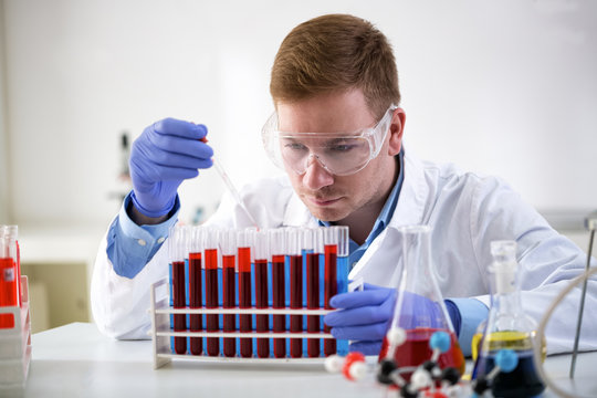 Concentrated chemist holding pipette and working at laboratory
