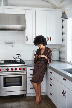 African American woman on her phone in kitchen