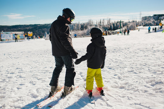 father teaching child how to ski
