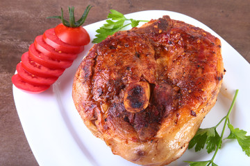 grilled pork chop with sliced tomato and sauce on wooden table.