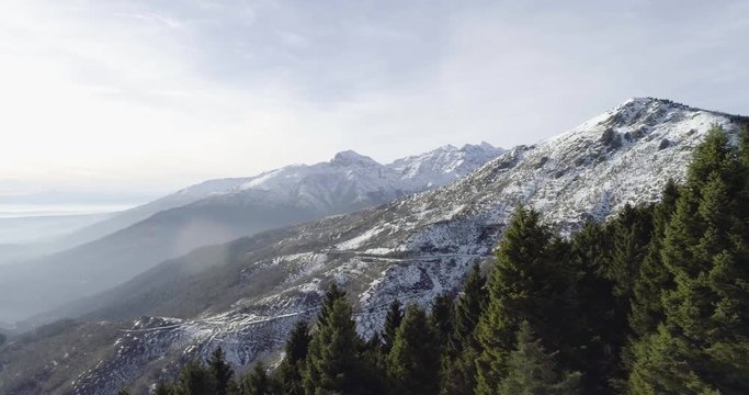 Forward aerial drone flight establisher over snowy forest woods with mountains in winter. Snow in mountain nature outdoors.Travel exploring Alps. 4k establishing video