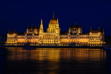 Panoramic view of Hungarian Parliament reflecting in Danube river. Night cityscape of Budapest