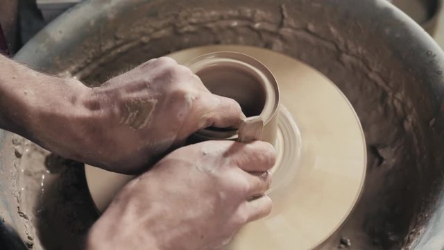 Hands of the master potter and vase of clay on the potter's wheel close-up. Master crock man. Twisted potter's wheel.