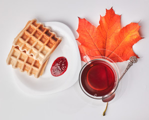 A cup of tea and crispy wafers./A cup of tea and crispy wafers poured with raspberry jam. White dishes. White background.