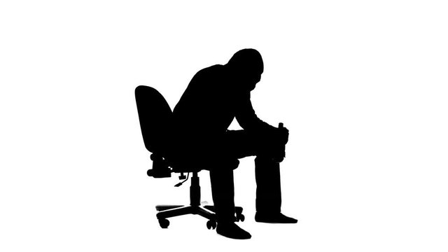 Alcoholic is sitting on the cheir and drinking from the bottle. Silhouette. White background