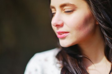 Portrait of a dreamy attractive woman meditating outdoors with eyes closed, with the effect of blur on a dark background closeup.