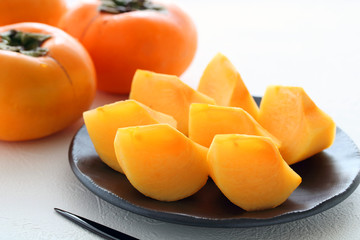 Fototapeta na wymiar Delicious sliced persimmons on black plate