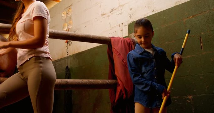 Mother and daughter cleaning stable 