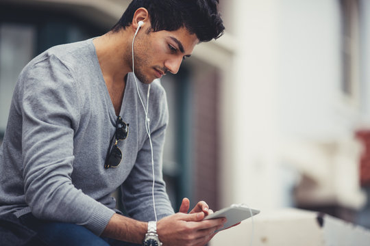 Mixed race man, seated outdoors with tablet