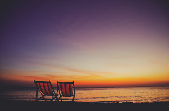 Two (2) empty and inviting beach chairs next to the sea during beautiful sunset on Koh Lanta island
