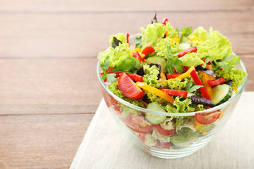 Vegetable salad in glass bowl on brown wooden table
