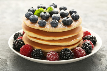 Tasty pancakes with berries on grey wooden table