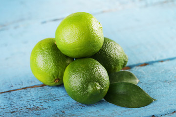 Ripe limes with green leaf on wooden table