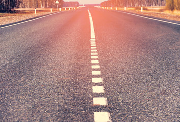 The picturesque landscape and the Sunrise over the road. Asphalt road with marking. With the blur...