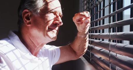 Senior man looking through window 