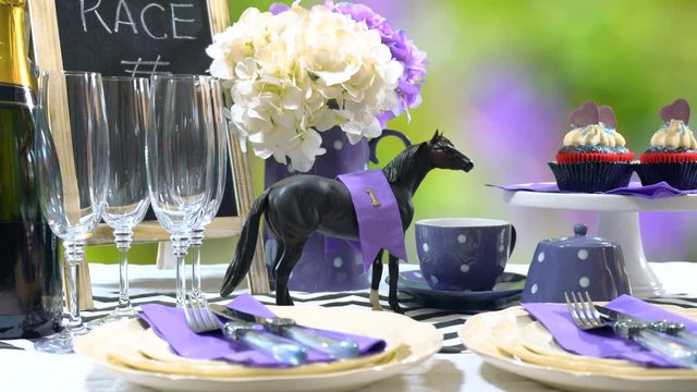 Horse racing Racing Day Luncheon fine dining table setting with small black fascinator hat, decorations and champagne, setting table.