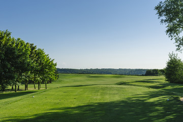 Fototapeta na wymiar General view of a green golf course on a bright sunny day. Idyllic summer landscape. Sport, relax, recreation and leisure concept