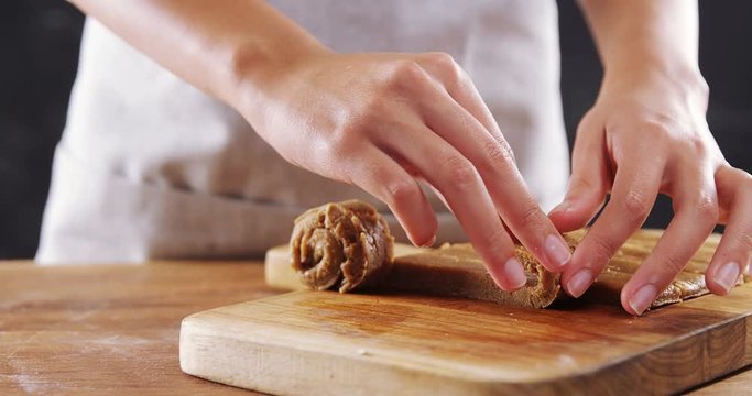 Woman rolling dough on chopping board 