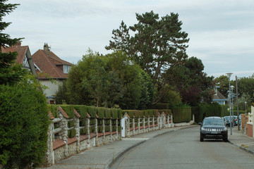 Country houses with green fences and streets in the region of Normandy, France. Beautiful countryside, lifestyle and typical french architecture, european country landscapes.