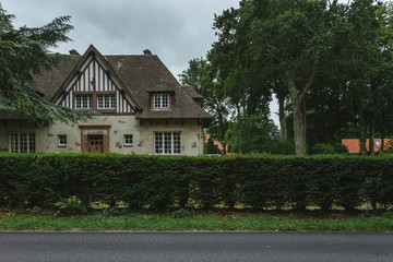 Country houses with green fences and streets in the region of Normandy, France. Beautiful countryside, lifestyle and typical french architecture, european country landscapes.