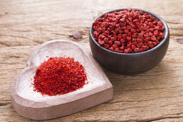 Achiote grains and powder in wooden bowl