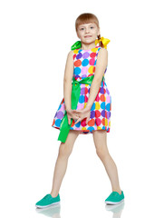 A little girl in a dress with a pattern from multi-colored circl