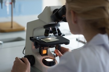 University student doing experiment on microscope in laboratory