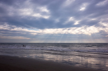 silhouettes of two people having fun in the ocean at sunset