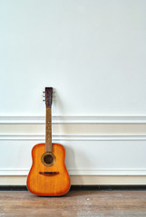 Fototapeta premium an ornamental wooden guitar stands beside a beige wall