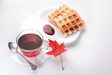 A cup of tea and crispy wafers./A cup of tea and crispy wafers poured with raspberry jam. White...