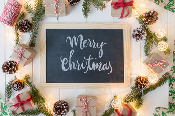 Christmas background with signboard and inscription, spruce, gift box and scroll on wooden boards.