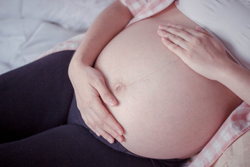 Close up of  pregnant woman  touching her belly .