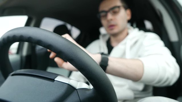 Young driver being impatient, waiting inside his car and showing signs of frustration.