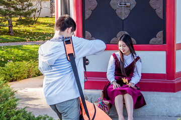 A young oriental girl is getting picture taken by an enthusiastic photographer	