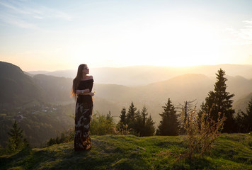 Beautiful girl, model in the mountains in the evening sun with a deep fog and perspective in...