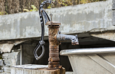 old rusty manual water pump. Wood base 