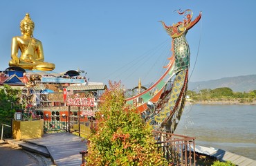 Золотой сидячий Будда в лодке на берегу меконга в храме Phra Chiang Saen Si Phaendin