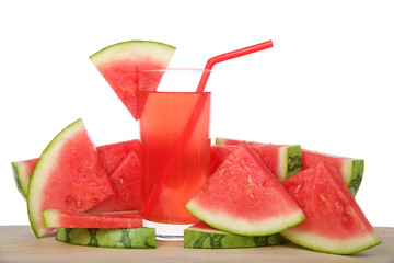 Glass of watermelon lemonade on a wood table surrounded by fruit. Red straw, slice of watermelon on side of cup, isolated on white background.