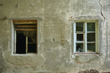 The old dirty broken window on the old dirty wall with cracks.