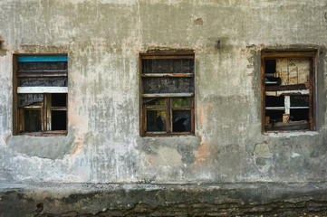 The old dirty broken window on the old dirty wall with cracks.