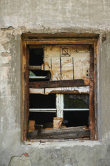 The old dirty broken window on the old dirty wall with cracks.