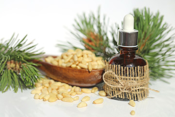 Obraz na płótnie Canvas pine oil. Pine essential oil in a glass bottle with a pipette, pine branches and pine nuts on a white background . Essential oil of coniferous tree.