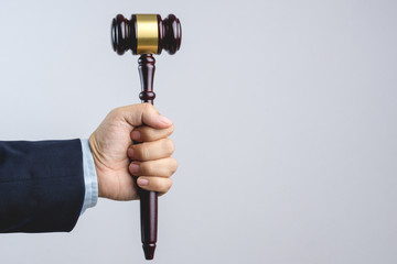 Business man hand holding wooden judge's gavel as a law or justice sign