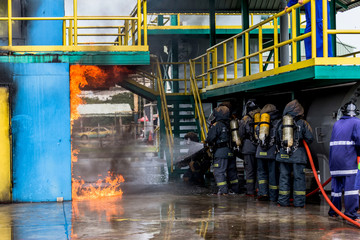 Firemen using water from hose for fire fighting at firefight training of insurance group. Firefighter wearing a fire suit for safety under the danger case.
