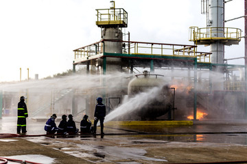 Firemen using water from hose for fire fighting at firefight training of insurance group....