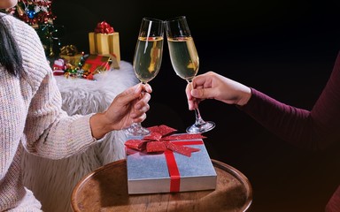 Christmas or New Year Celebration people hands with crystal glasses full of champagne near the Christmas tree and space for your text.