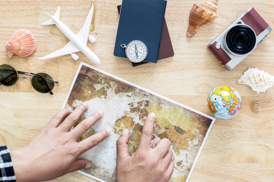 Young man planning travel on vacation trip with map. Top view.