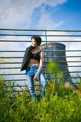 young woman dressed in white sneakers, black top and blue jeans, on a background of urban landscapes. Street fashion