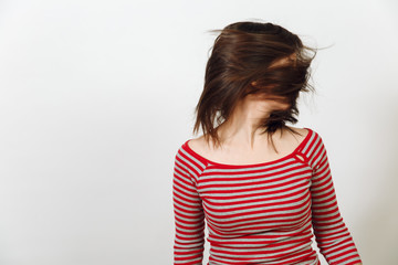 Beautiful European young happy brown-haired woman, dressed in casual red and grey clothes, waving long healthy clean hair on a white background. Emotions concept.